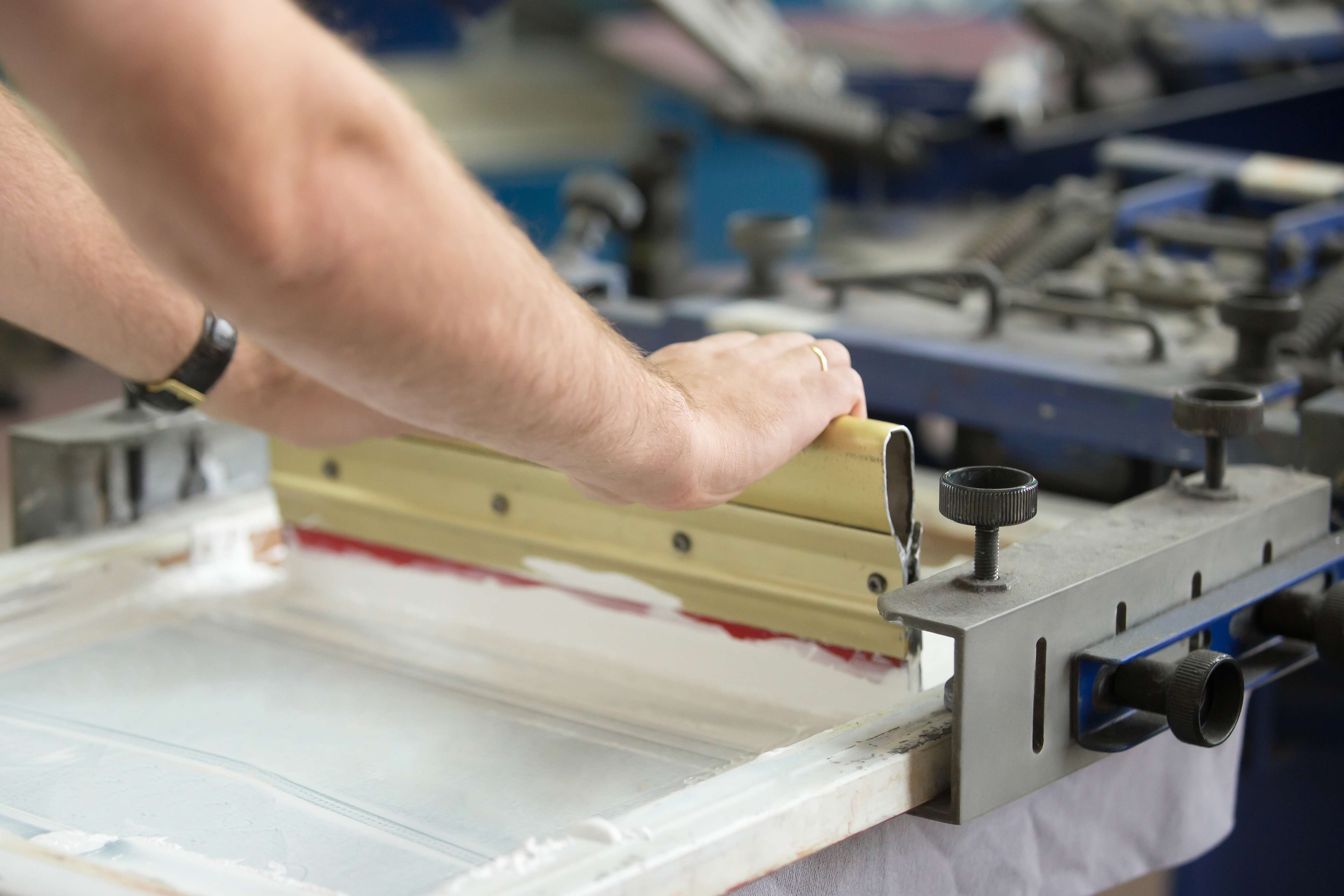 Person using silkscreen printing method for printing on the meal surface.