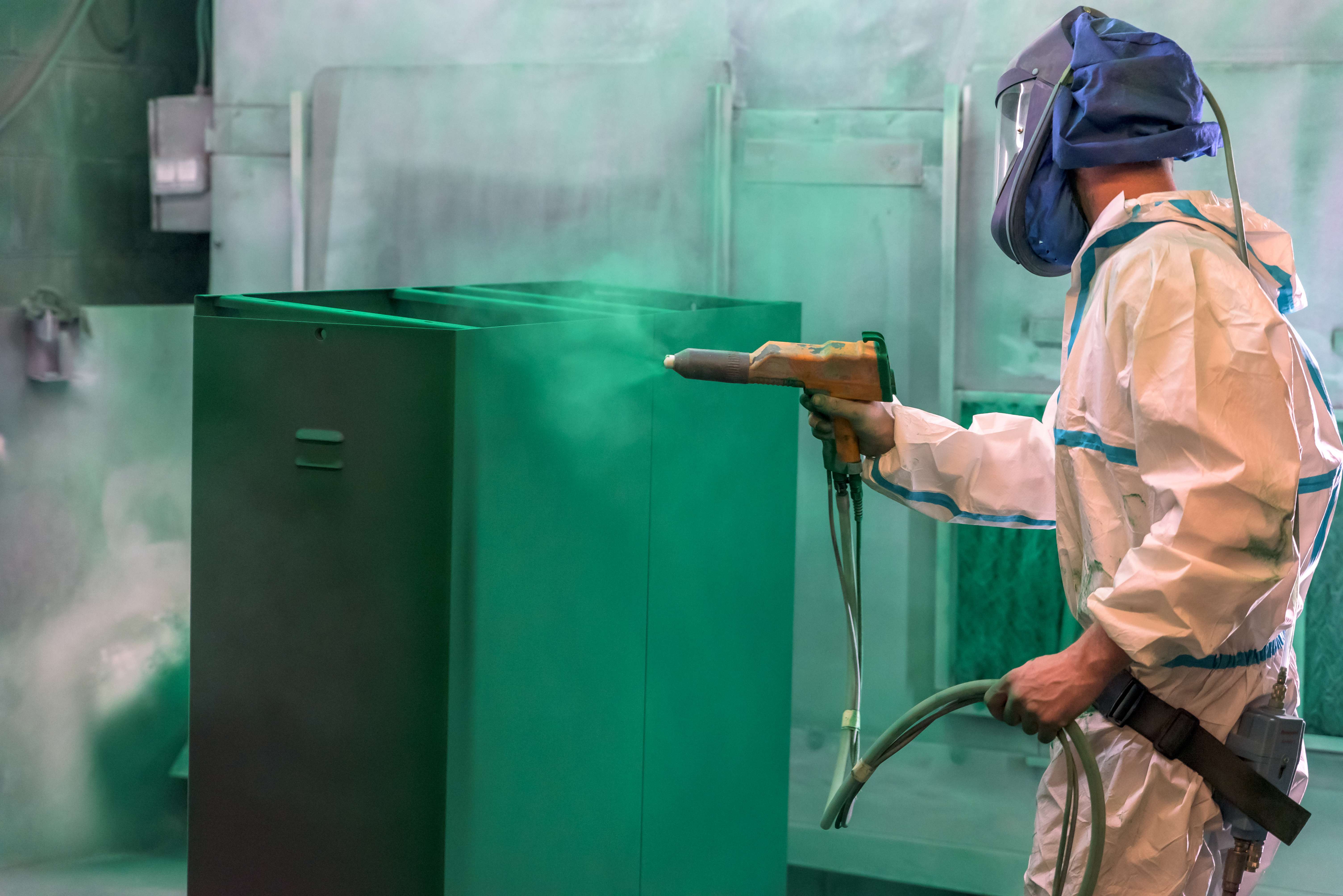 Person coating a cabinet made with shhet metal to protech the surface.