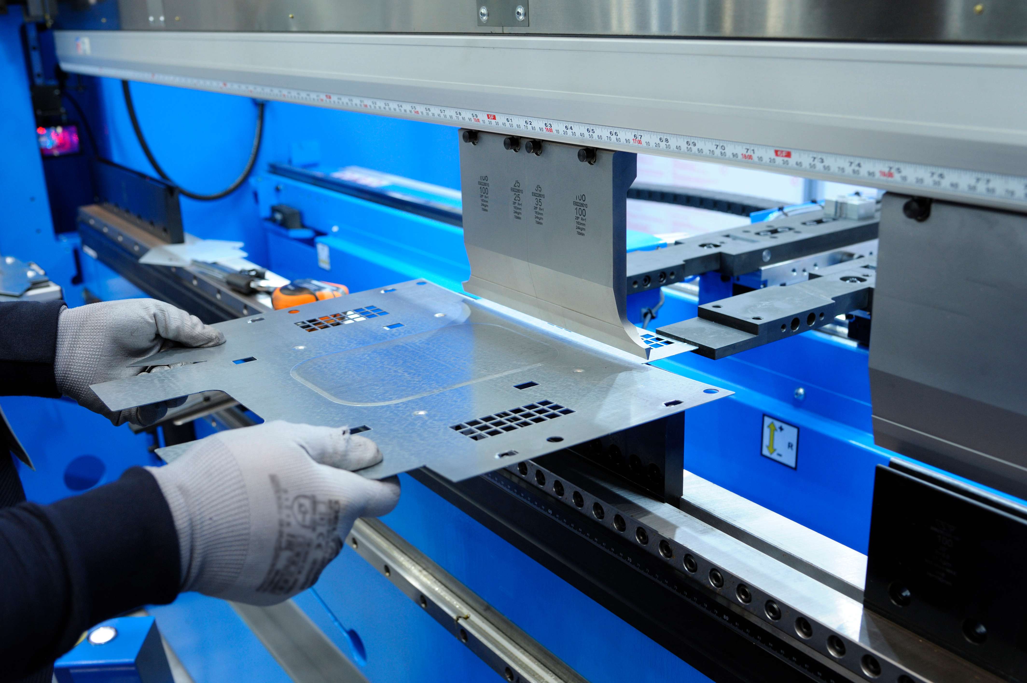 Person making custom designed sheet metal part on a brake press.